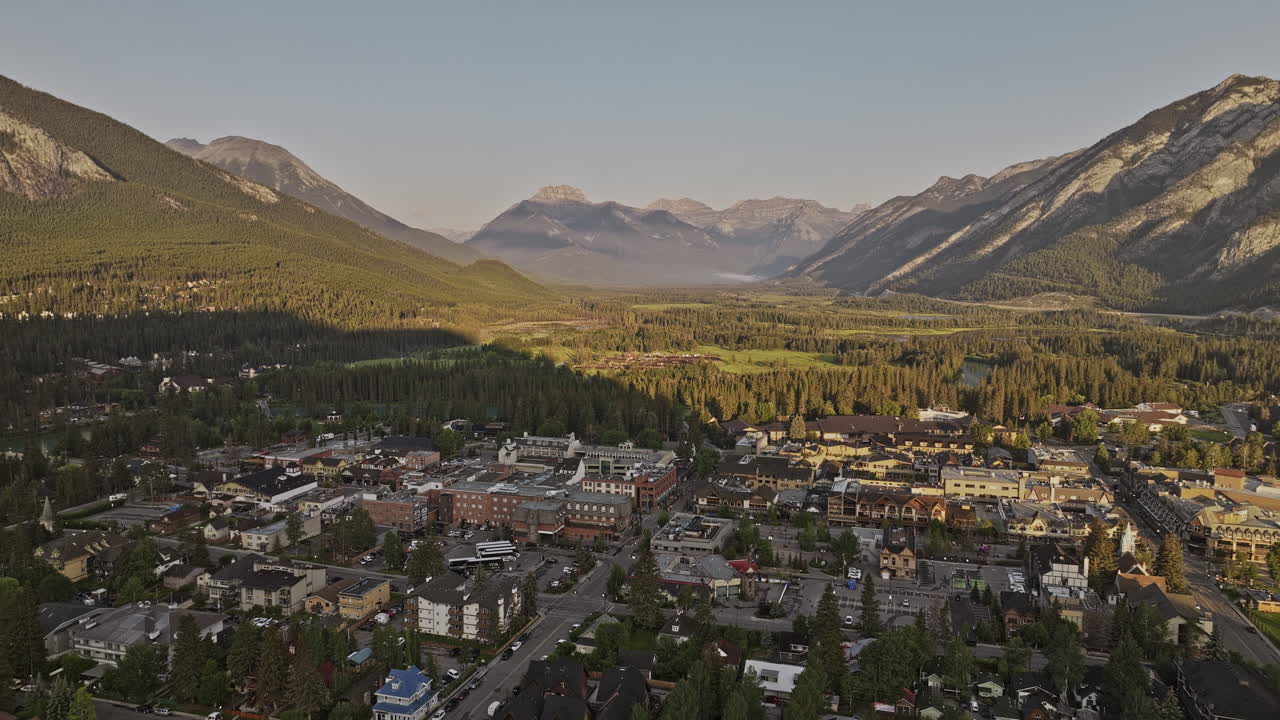 banff ab canada aerial v23 sobrevuela el centro de la ciudad y el río bow capturando casas residenciales, establos de caballos y luz solar en valles boscosos y cadenas montañosas - filmado con mavic 3 pro cine - julio 2023
