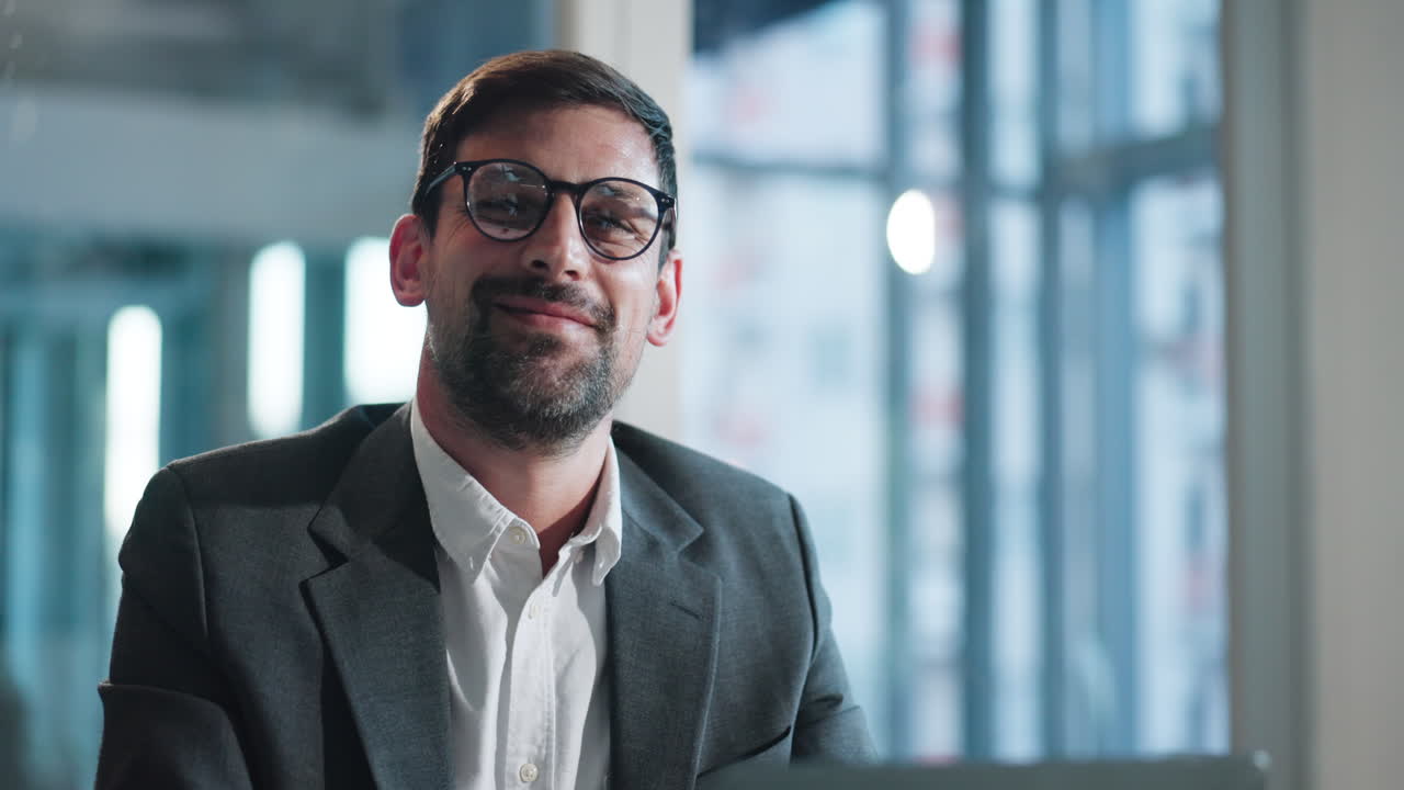 Glad forretningsmand med briller smiler til kameraet på et moderne kontor