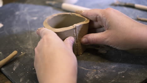 hands shaping clay cup