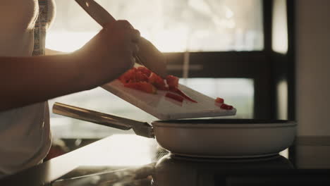 Woman-pouring-chopped-vegetables-into-a-frying-pan