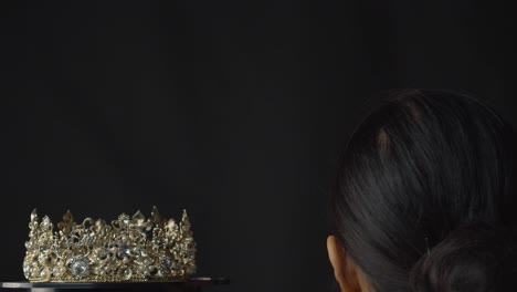 beauty pageant queen or bride places a diamond, pearl and silver crown on her head - black background