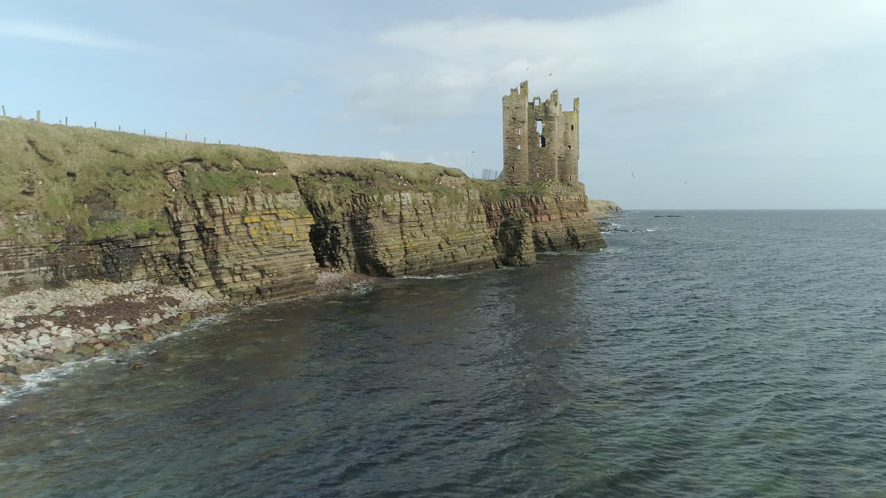 toma aérea ascendente moviéndose a lo largo de la costa hacia el castillo de keiss en un día soleado, caithness, escocia