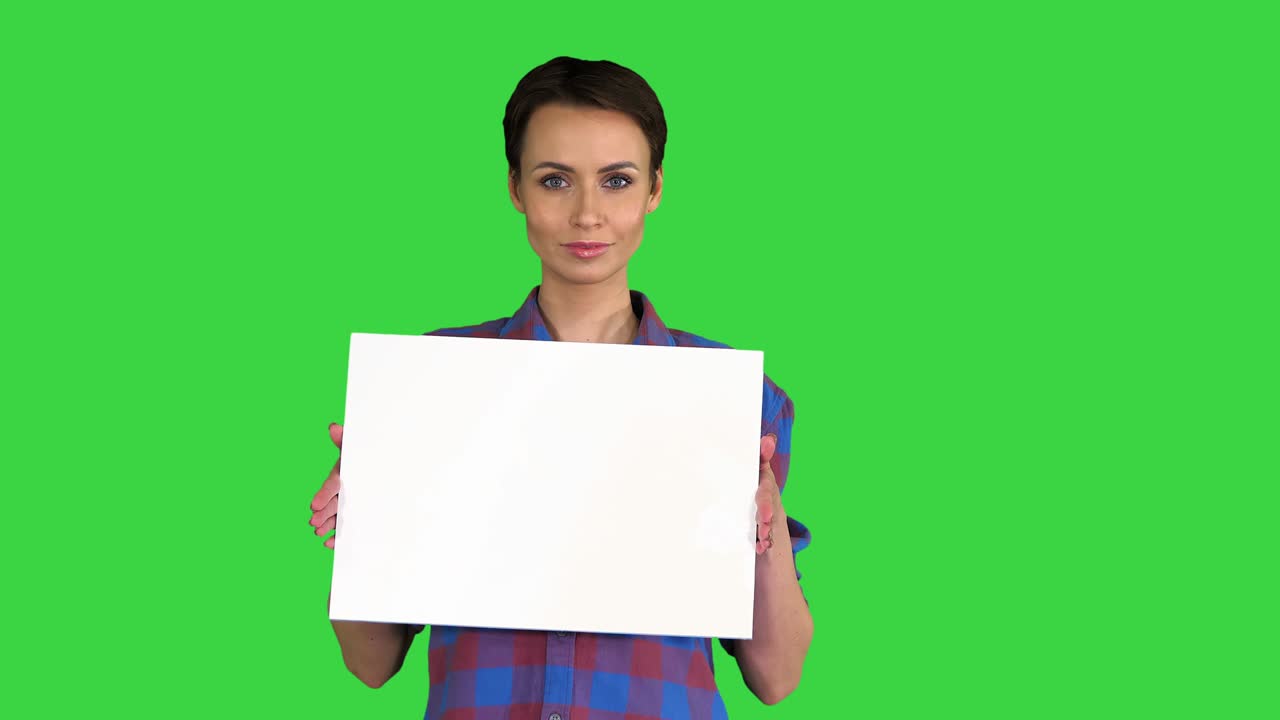 Donna attraente mostra un poster bianco vuoto su uno schermo verde, Chroma Key.