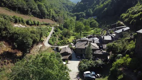 Toma-Aérea-Hacia-Atrás-Desde-Un-Pequeño-Pueblo-En-El-Valle-De-Las-Verdes-Montañas-De-Asturias,-España