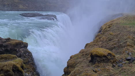 powerful waterfall in landscape of iceland, glacial water flowing into deep narrow canyon