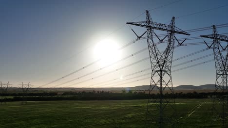 pista de drones a lo largo de líneas eléctricas con el sol en el fondo