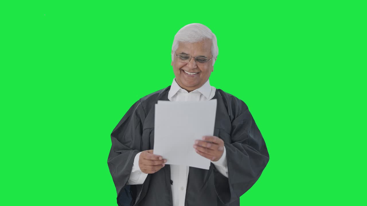 Happy Indian senior lawyer reading court case papers Green screen