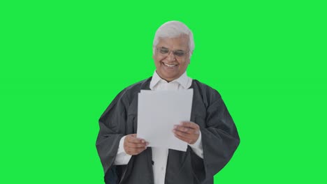 un abogado senior indio feliz leyendo papeles de casos judiciales pantalla verde