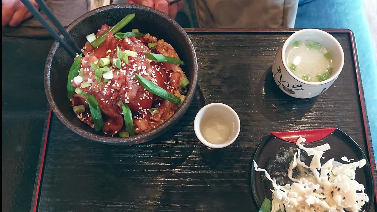 Overhead view of eating a bowl of maguro zuke don or marinated raw tuna rice bowl, an authentic local Japanese dish