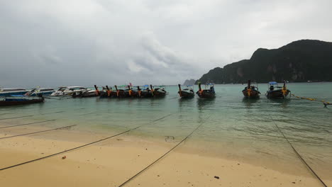 famous touristic thai excursion boat lands on, cloudy day on koh phi phi island