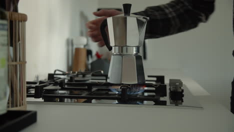 macho preparando café con la tradicional cafetera bialetti moka express en una estufa de gas por la mañana