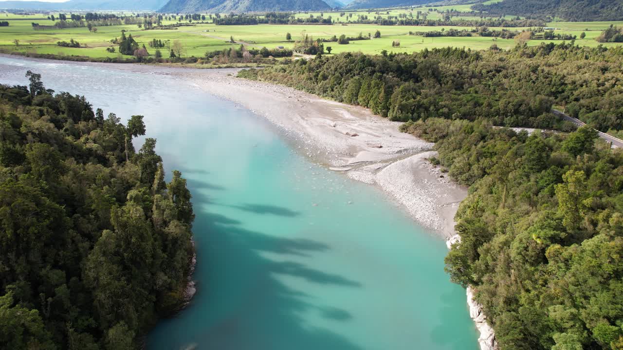 Hokitika River's Turquoise Water Flowing Through Vegetation In West Coast Of South Island, New Zealand. drone shot