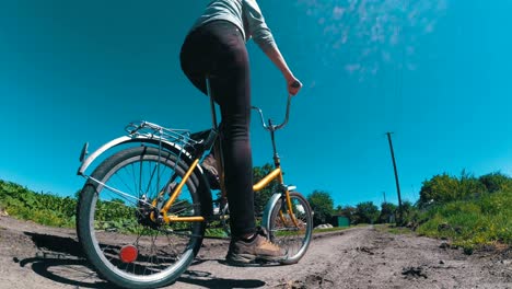 young woman riding vintage bicycle along a rural road in a village