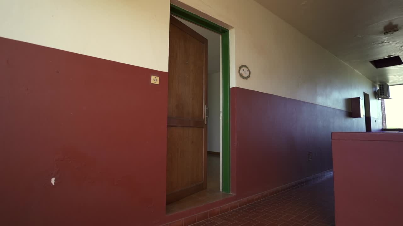 Smooth, forward moving slider clip highlights private apartment door in vibrant red and white staircase hall, during afternoon sunlight. Perfect for rental listings.