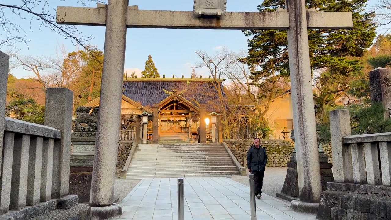 Mężczyzna idzie przez kamienną bramę torii w kierunku świątyni shintoistycznej w Kanazawie w Japonii.