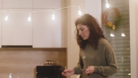 Mujer-Morena-Colocando-Cosas-En-La-Mesa-Decorada-Con-Velas-Y-Un-Mantel-Para-La-Cena-De-Navidad