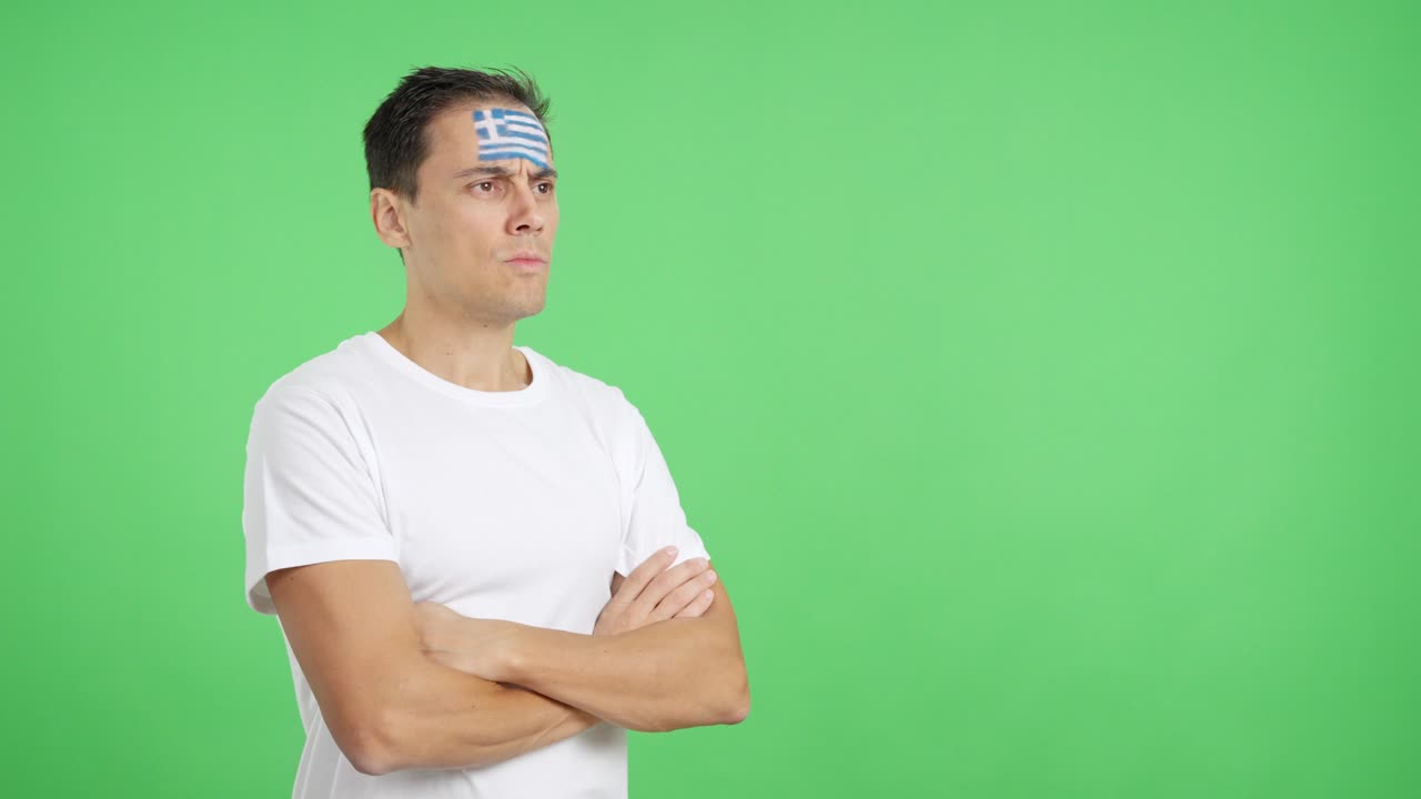 Man with greek flag painted looking away with serious expression