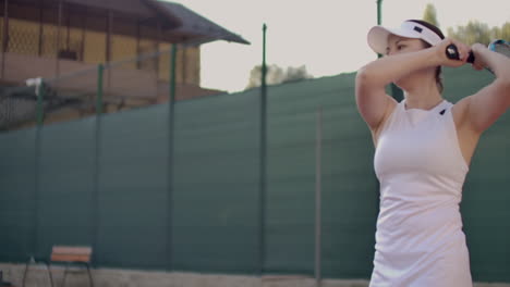 close-up of woman holding tennis racket in both hands to straighten strike. close-up of young attractive woman playing tennis at tennis court. player holding outfit. slow motion