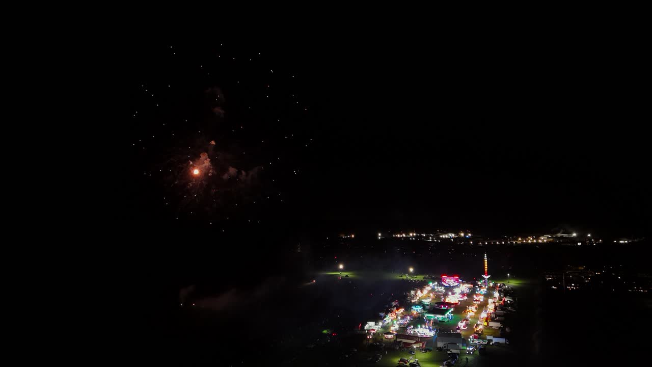 Colorful fireworks over a lively Thetford fair at night, joyous atmosphere