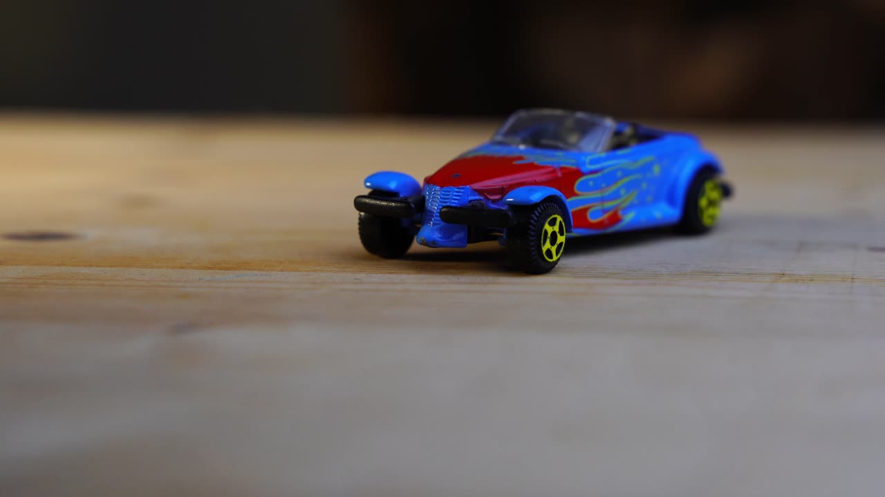 나무 탁자에 있는 작은 빨간색 파란색 장난감 자동차가 회전합니다.