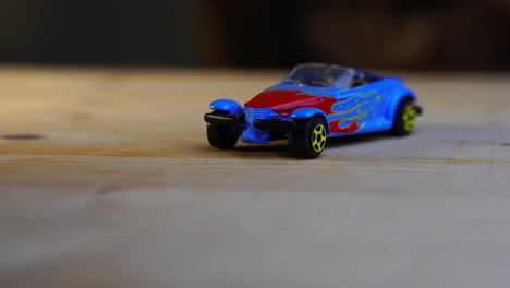 small-red-blue-toy-car-convertible-on-wooden-table-rotates