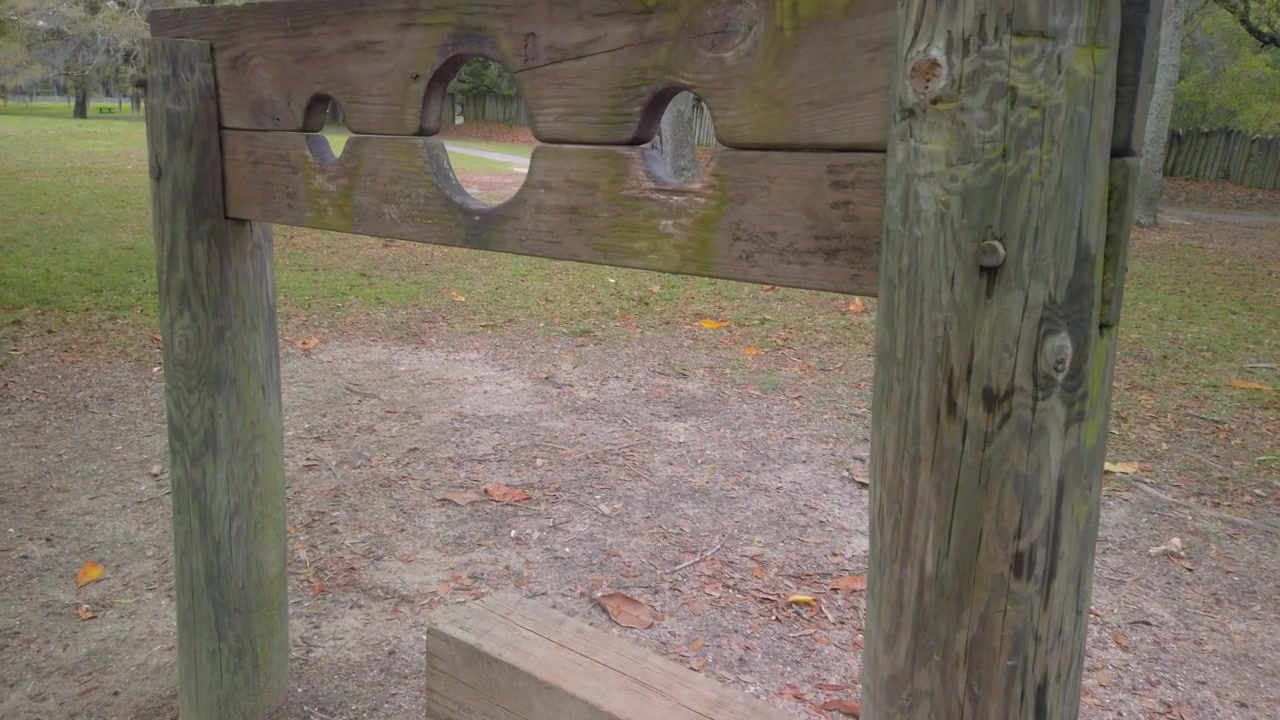Gimbal close-up panning shot of a recreated 17th century wooden pillory at Old Charles Towne Landing in South Carolina. 4K