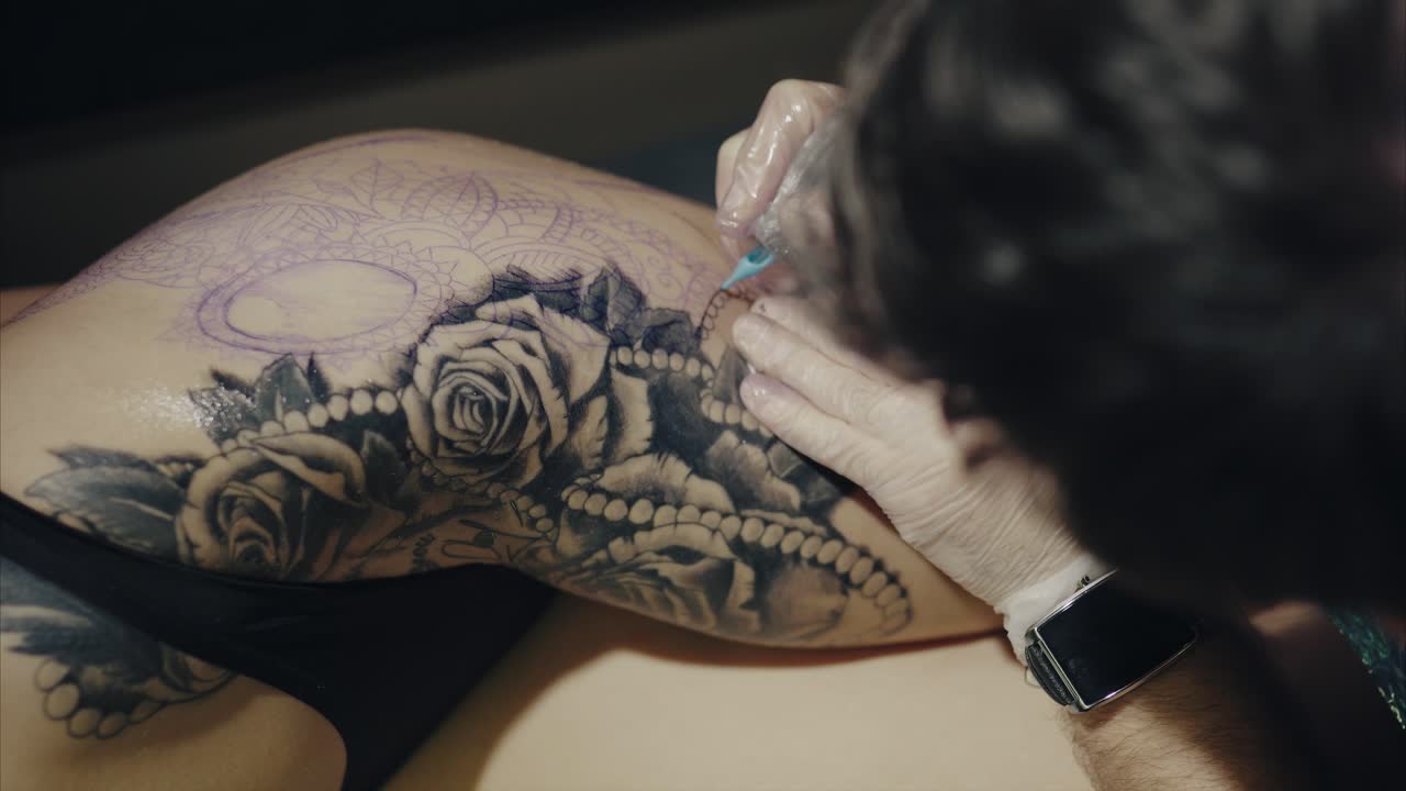 Tattoo Artist Working on a Thigh Tattoo