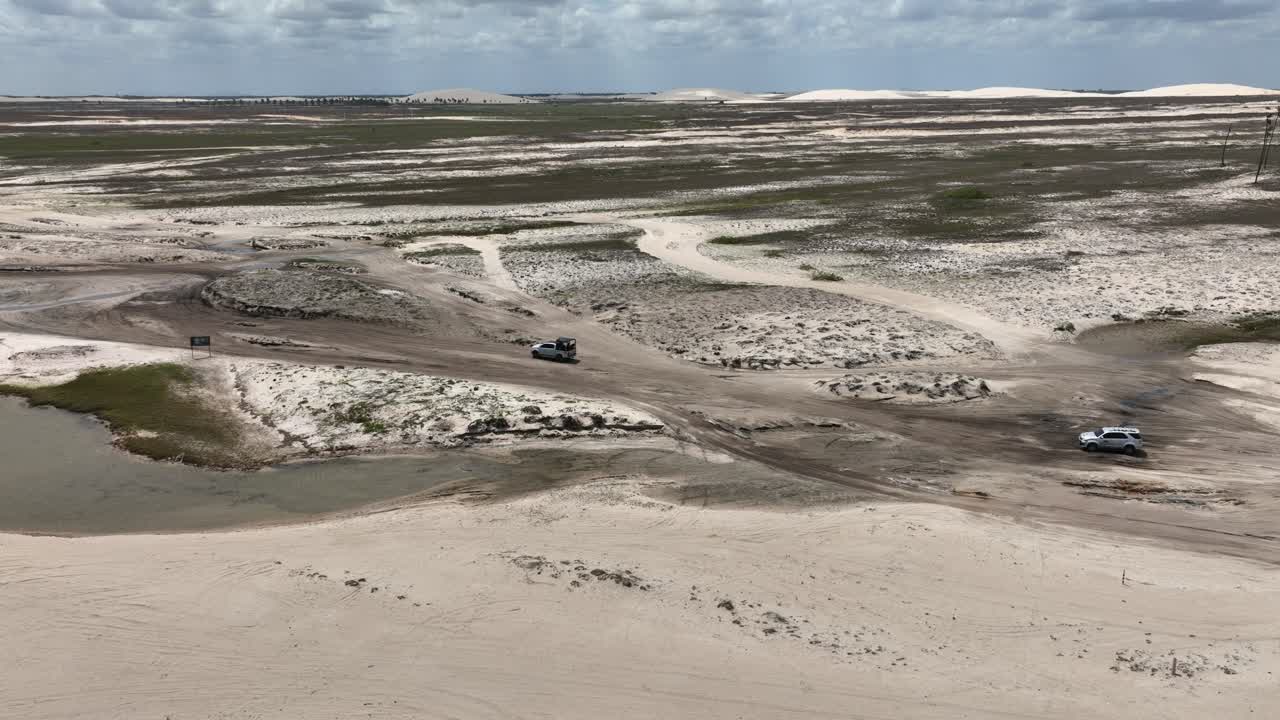 Wide angle aerial view of a car driving through sandy surface of Jericoacoara in Brazil