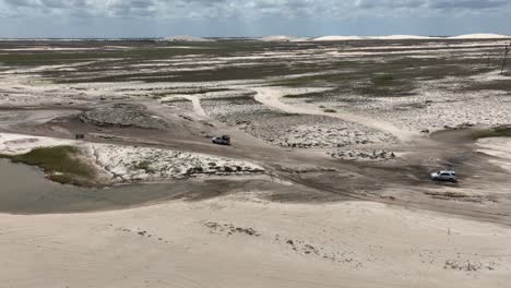 wide angle aerial view of a car driving through sandy surface of jericoacoara in brazil