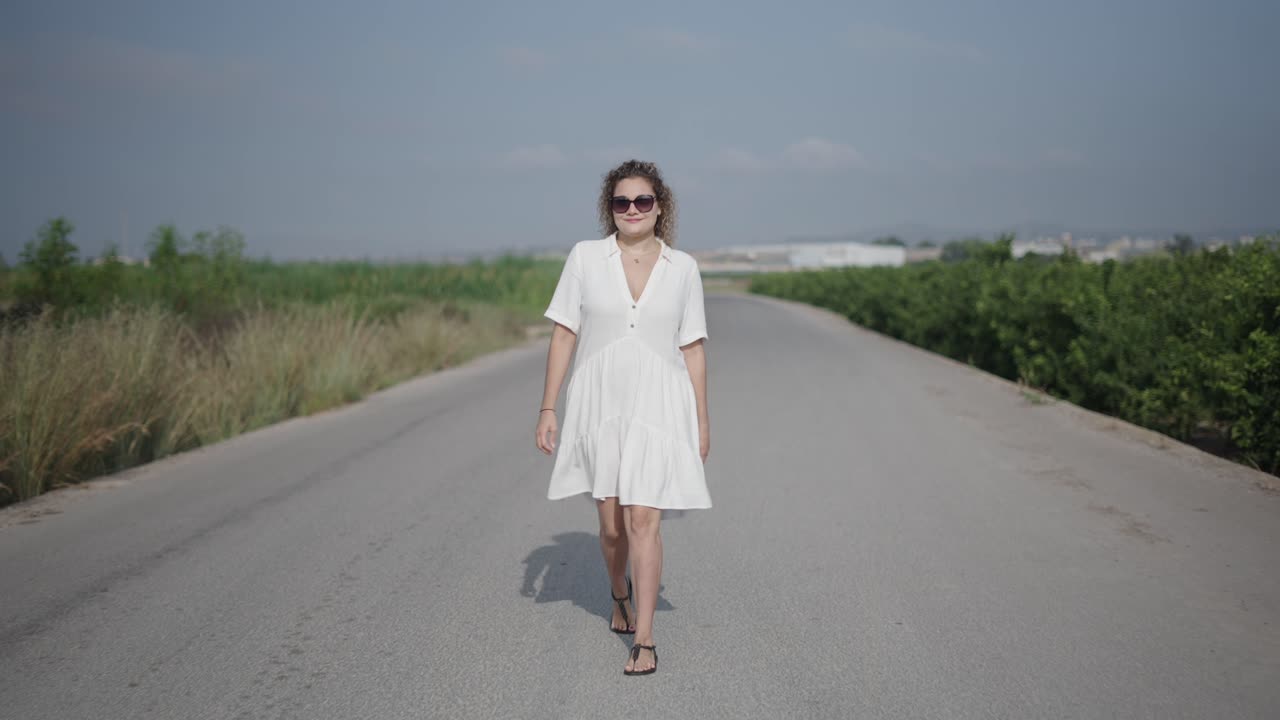 Donna che cammina lungo una strada di campagna in abito bianco