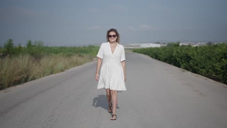 woman walking down a country road in a white dress