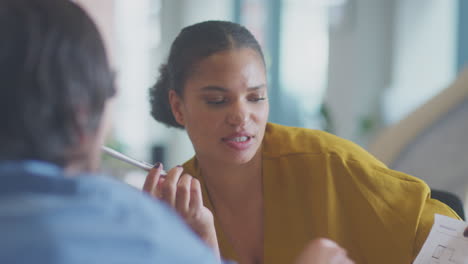 Close-Up-Of-Businessman-And-Businesswoman-Having-Meeting-Sitting-Around-Table-In-Modern-Office