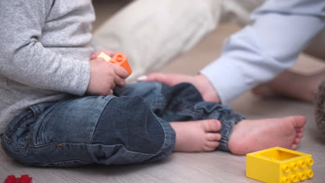 vista de cerca de un bebé sentado en el suelo jugando con bloques de construcción cerca de su madre