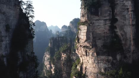 Drone-push-in-past-mystical-cliff-valleys-between-mountain-spires-zhangjiajie,-Wulingyuan-Hunan-China