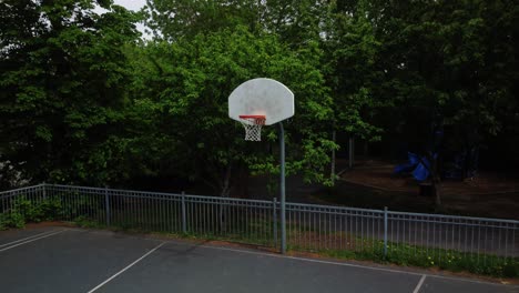 basketball net with green trees in background, aerial shot, dolly out