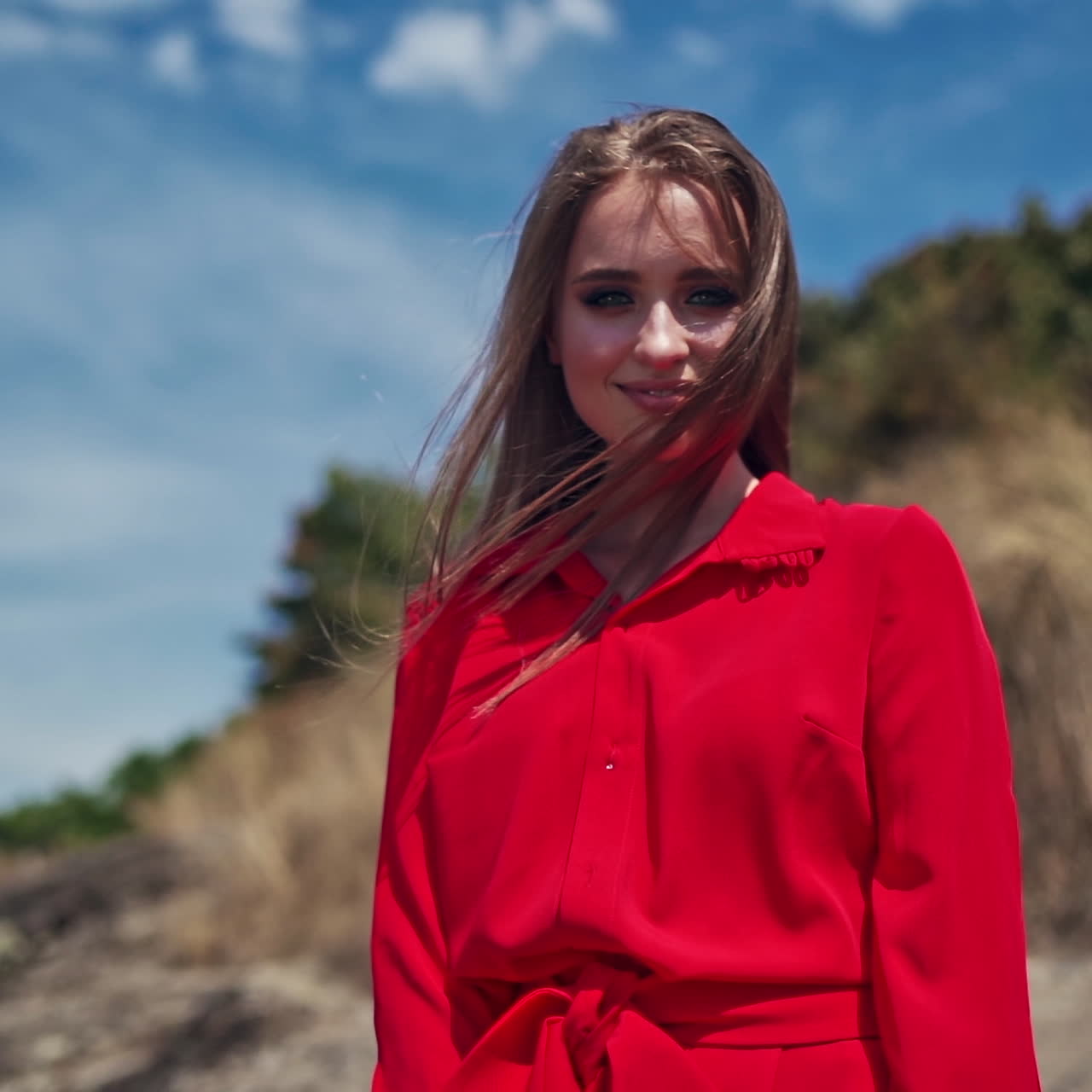 Portrait of a smiling girl outdoors. Beautiful young woman looking at camera. Happy attractive female with long hair standing in nature.