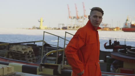 joven trabajador en uniforme naranja caminando por el puerto junto al mar durante su descanso. tiempo libre