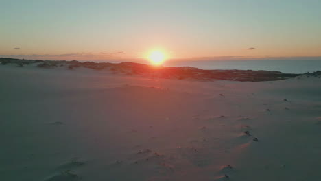drone sand dunes sunset view. sunset descending casting golden glow at ocean