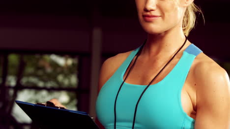 una entrenadora sonriente con un clipboard y un cronómetro