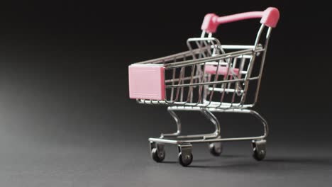 Empty-shopping-trolley-on-seamless,-lit-black-background-with-copy-space