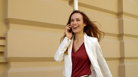 happy businesswoman walking with mobile phone outdoors