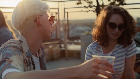 caucasian couple talking together at the roof top party during the sunset.