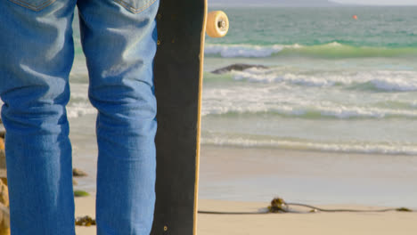 rear view of young man standing on the beach and looking at sea 4k