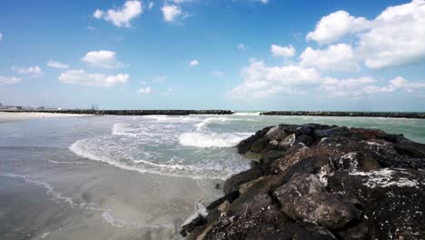 a stunning early morning view of rushing waves crashing against the breakwater at the beach
