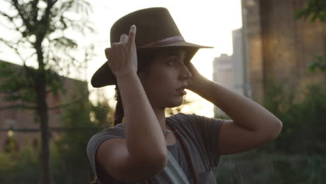 young woman putting on hat in urban setting