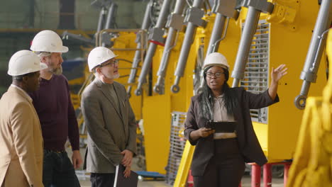 female manager giving factory tour to businessmen