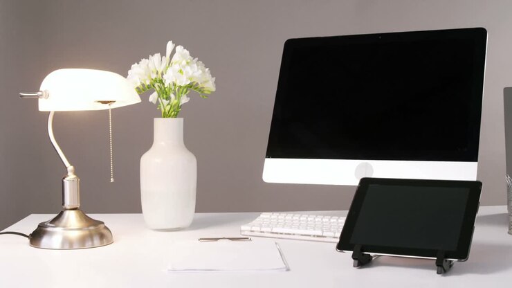 Computer, digital tablet, bordlampe og blomstervase