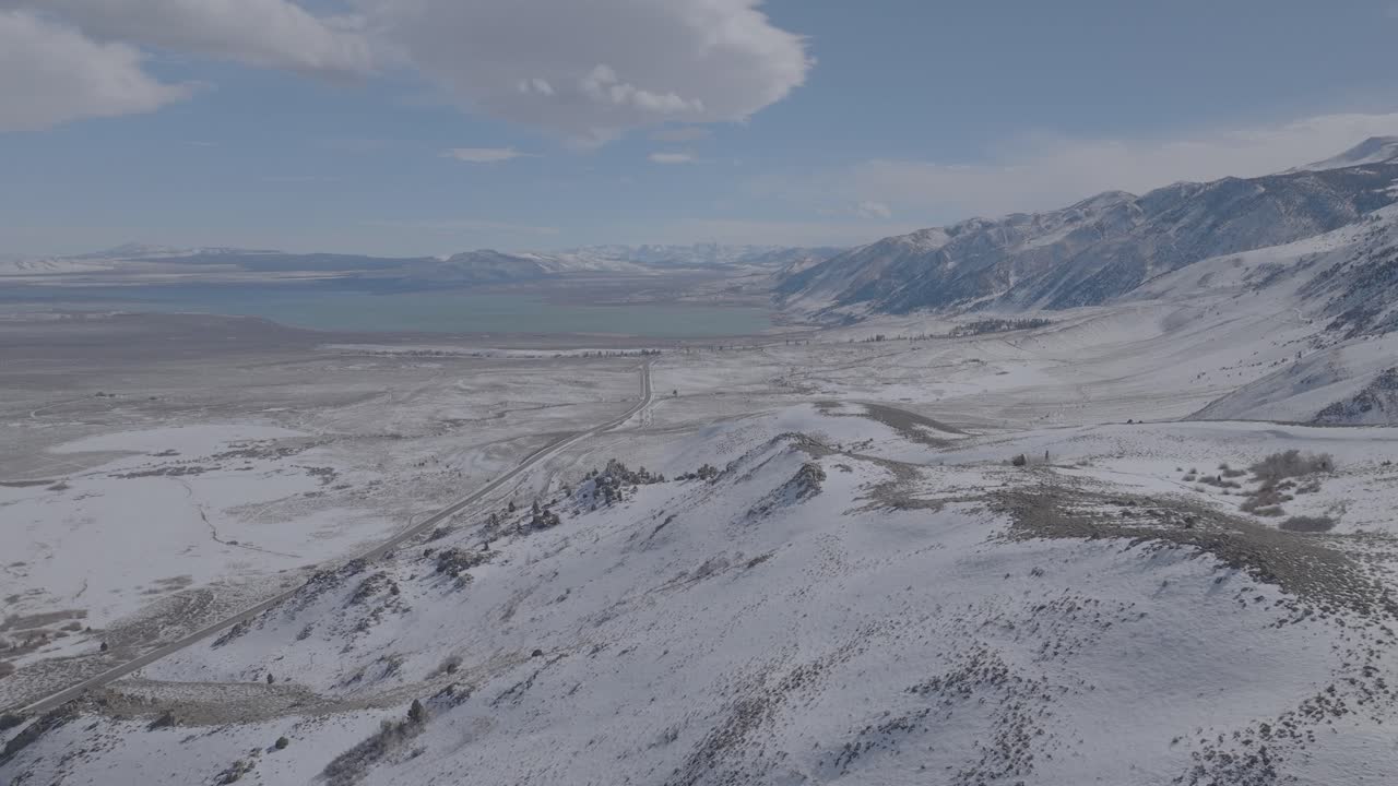 Aerial view of Lake Tahoe's snow-covered mountains and dense evergreen forest. Bright sunny winter day with blue sky. 4K drone video capturing pristine alpine wilderness and forested mountain terrain