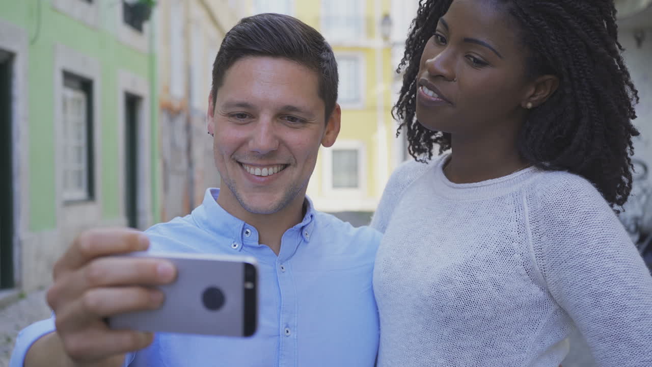 Vista frontale di giovane coppia allegra che si scatta un selfie con lo smartphone