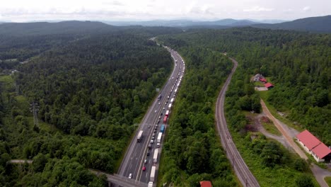 Overpass-overlooking-long-line-of-cars-and-trucks-forming-a-traffic-jam-on-an-European-highway-due-to-heavy-traffic-and-car-accident-surrounded-with-tall-trees-and-railroad